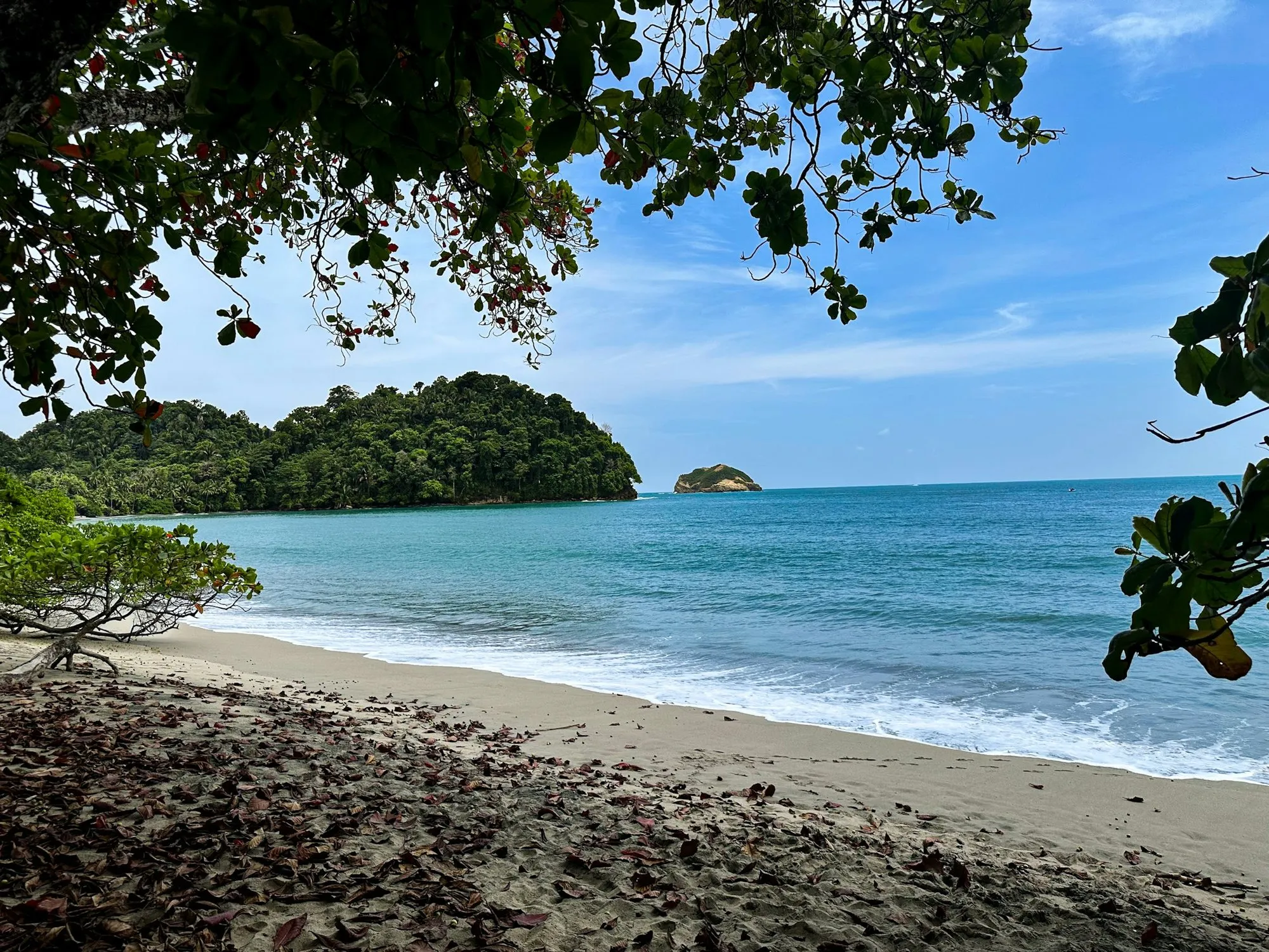 A beach in Manuel Antonio with calm water and forested islands offshore